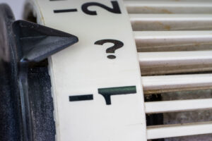 Radiator thermostat dial with a question mark, heat network regulation for landlords