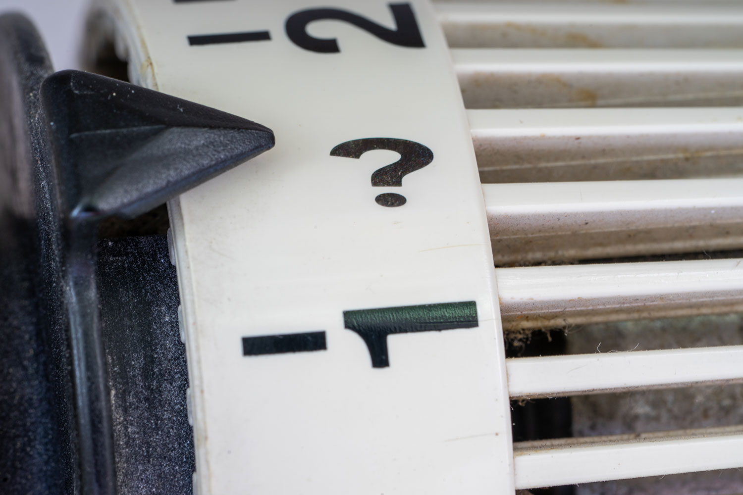 Radiator thermostat dial with a question mark, heat network regulation for landlords
